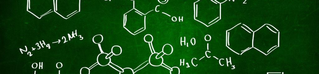 Green chalkboard with various hand-drawn organic chemistry structures and chemical equations, including benzene rings, hydroxyl groups, and molecular formulas like N₂ + 3H₂ → 2NH₃, representing chemical reactions and compounds.