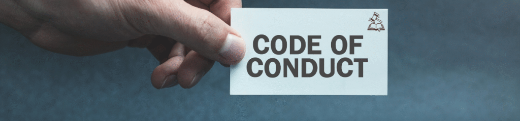 A close-up of a hand holding a white card with the words “CODE OF CONDUCT” printed in bold letters.