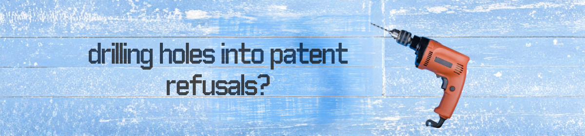 A blue wooden background with the words “drilling holes into patent refusals?” in black text, alongside an orange power drill angled toward the text.