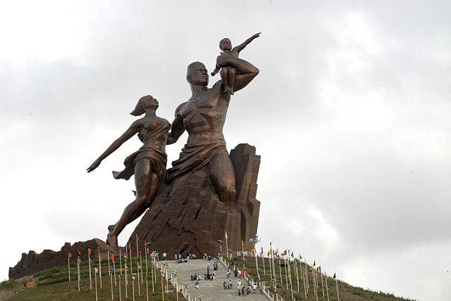 The image depicts the statute of a woman and a man holding a child sitting on a rock i.e., the African Renaissance statue.