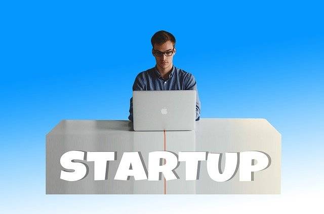 The image depicts a man using his laptop and a 'startup' text in front.