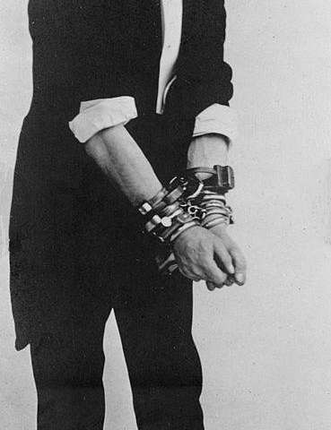 This image depicts Harry Houdini in handcuffs.