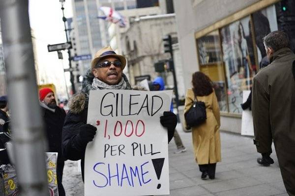 This image depicts a person holding a placard reading GILEAD 1,000 per Pill, Shame. This image is relevant as Gilead had filed for a patent for the same medicine in India for the same price. Click on the image for more information