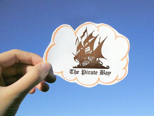 The featured image is of a hand holding the paper cut out of the pirate bay logo which is a pirate ship. The image is pertinent to the post as it is about the acquittal of the Pirate bay founders in a copyright infringement case in Belgium. To read the post click here.