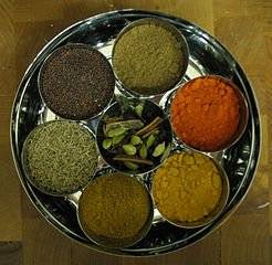 The image depicts a round plate with various spices like turmeric, cumin seeds, cinnamon, fenu greek placed on it. This post relates to traditional knowledge. For more information click here.